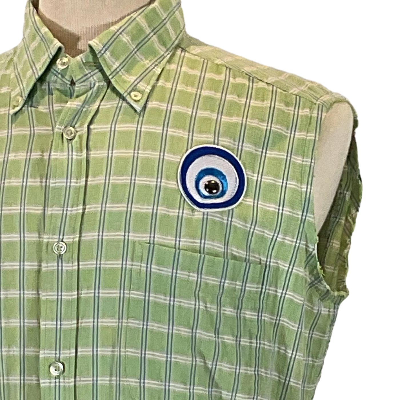 TYPEWRITER Men's Custom Sleeveless Shirt featuring a green and white plaid pattern with a unique blue eye patch design, showcasing bold, distinctive style.