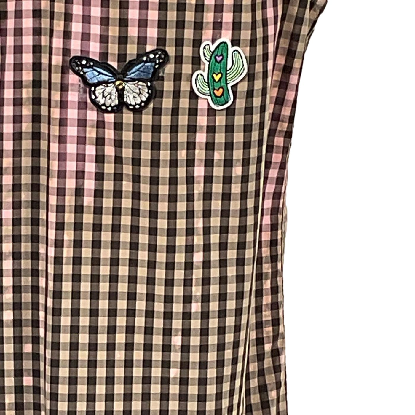 THINGS JUST GOT WEIRD Men's Custom Sleeveless Shirt featuring unique pin designs of a butterfly and cactus, set against a patterned textile backdrop.