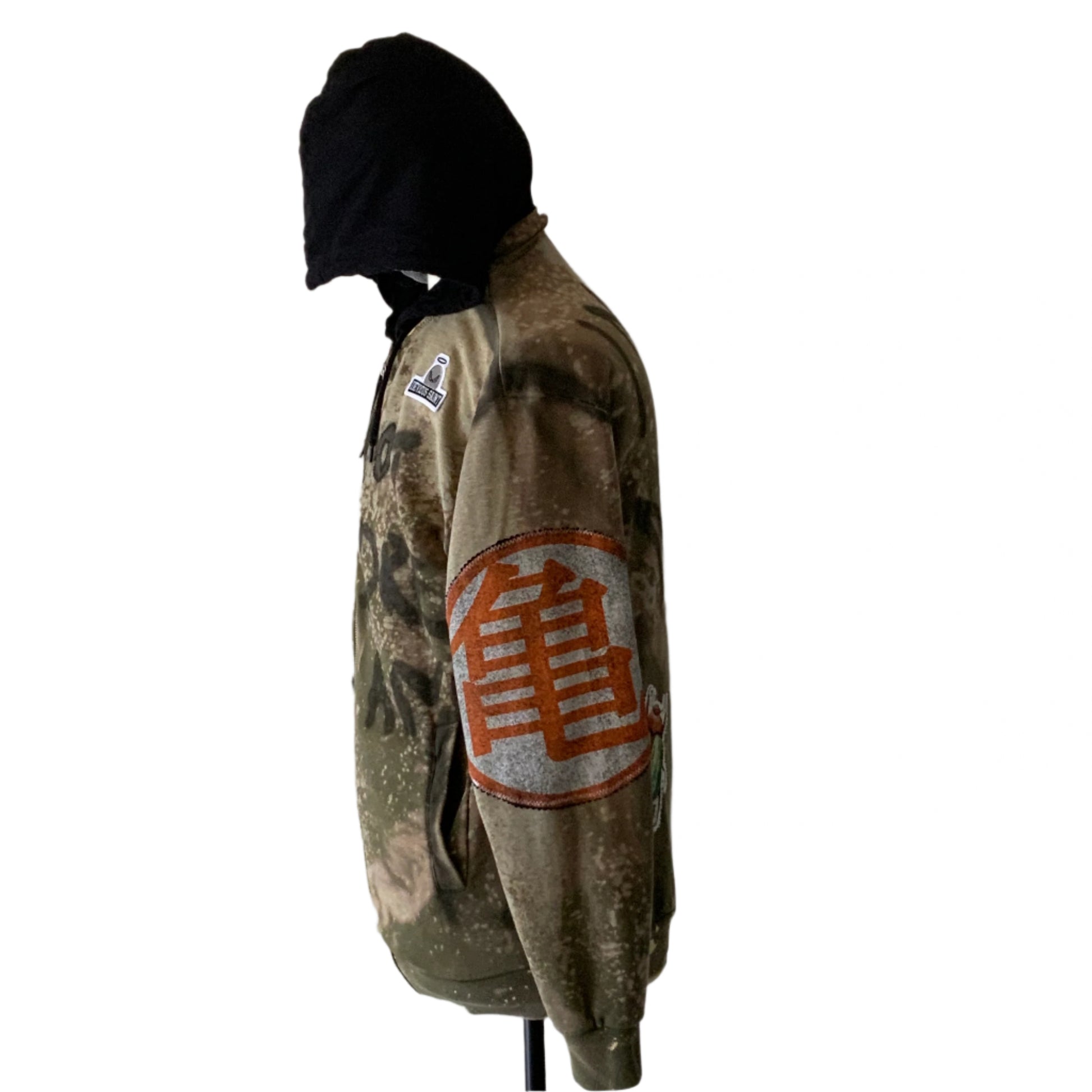 I’M NOT THE DREAM hoodie: Camouflage earth tones, black hood lining, kangaroo pocket, orange turtle kanji on sleeve, logo patch on chest.