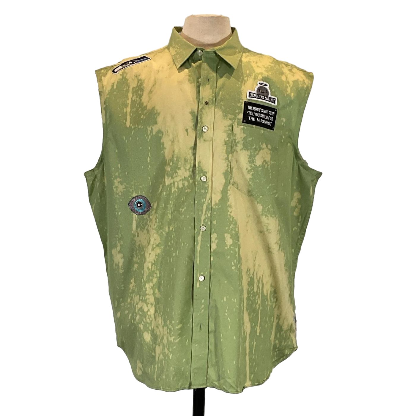 Green sleeveless shirt with patches, titled THANK YOU FOR LEAVING ME..., displayed on a mannequin, showcasing distinctive wearable art.