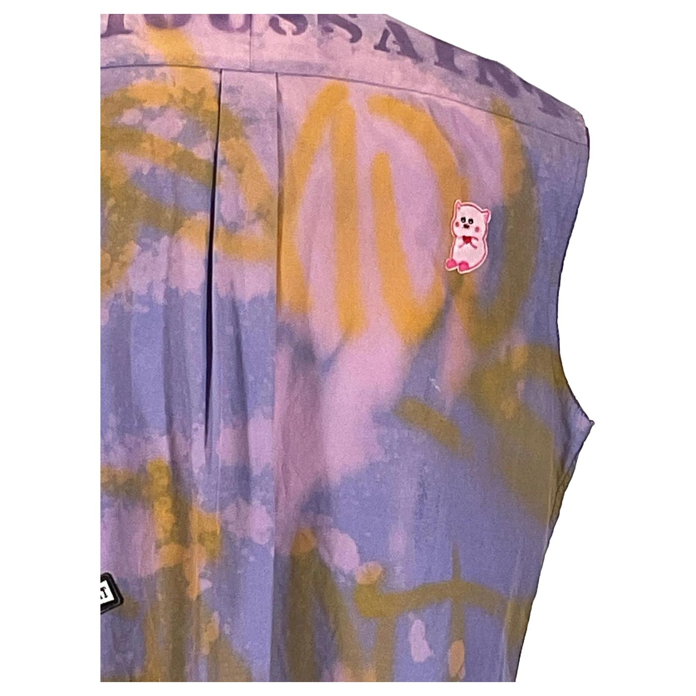 DEVIOUS SAINT Men's Custom Sleeveless Shirt featuring a tie-dye pattern with a unique pin, showcasing bold, artistic design on a fabric canvas.