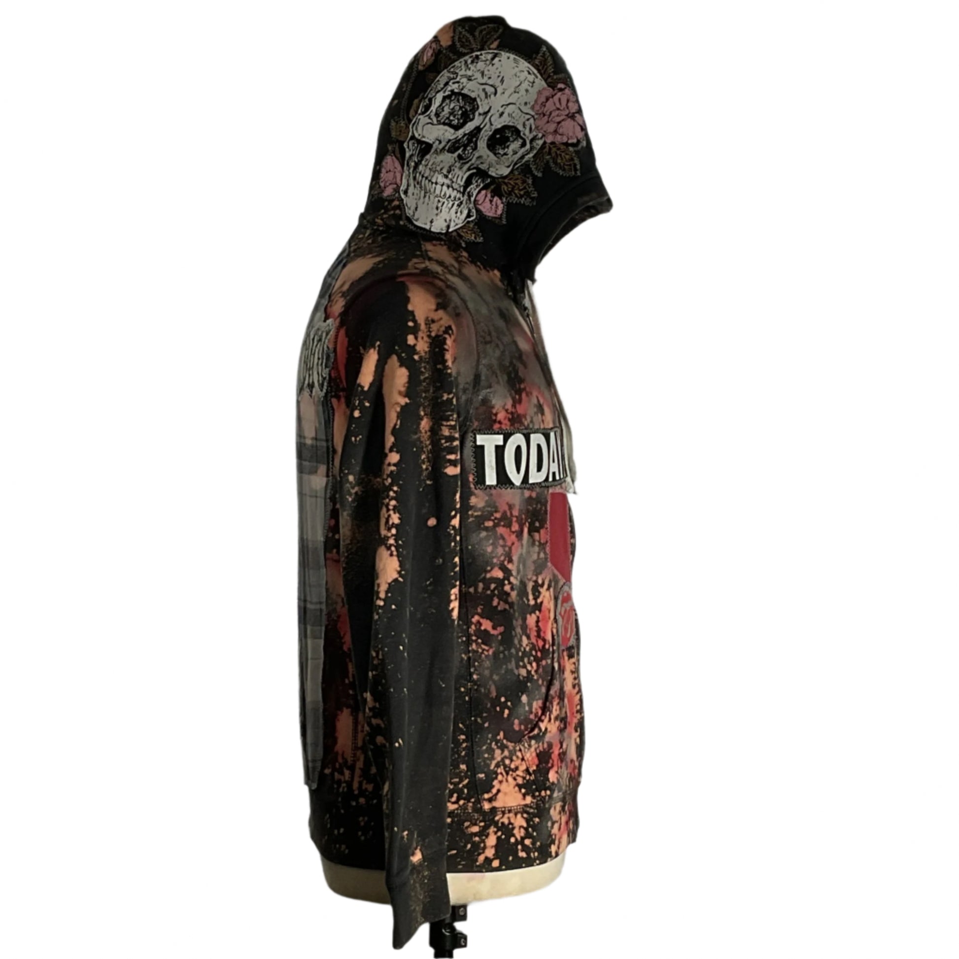 Person wearing the AFFLICTION Custom Men's Hoodie in Large, featuring a skull design, reflecting Devious Saint's unique, bold style. Mannequin displays similar hoodie indoors.