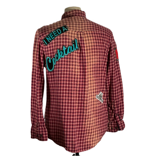 Close-up of a unique flannel shirt with hand-patched details and metal studs, showcasing a vintage aesthetic and sustainable craftsmanship by DEVIOUS SAINT.