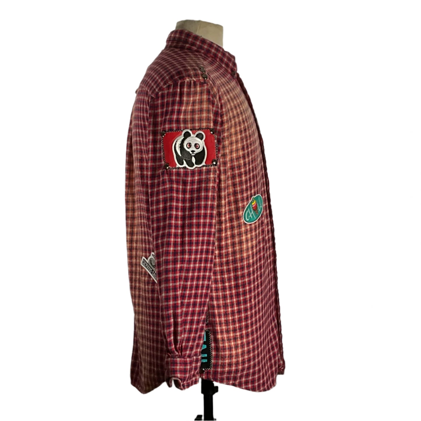 Red plaid flannel shirt with patches and metal studs, showcasing a vintage aesthetic and sustainable fashion. Unique, bold design in size Medium.