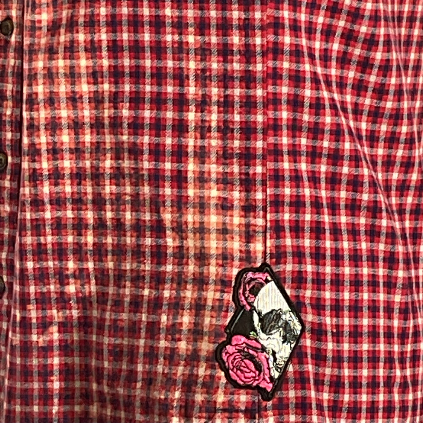 Red and black plaid flannel shirt with bleached treatment and hand-patched details, showcasing a vintage aesthetic and sustainable fashion.