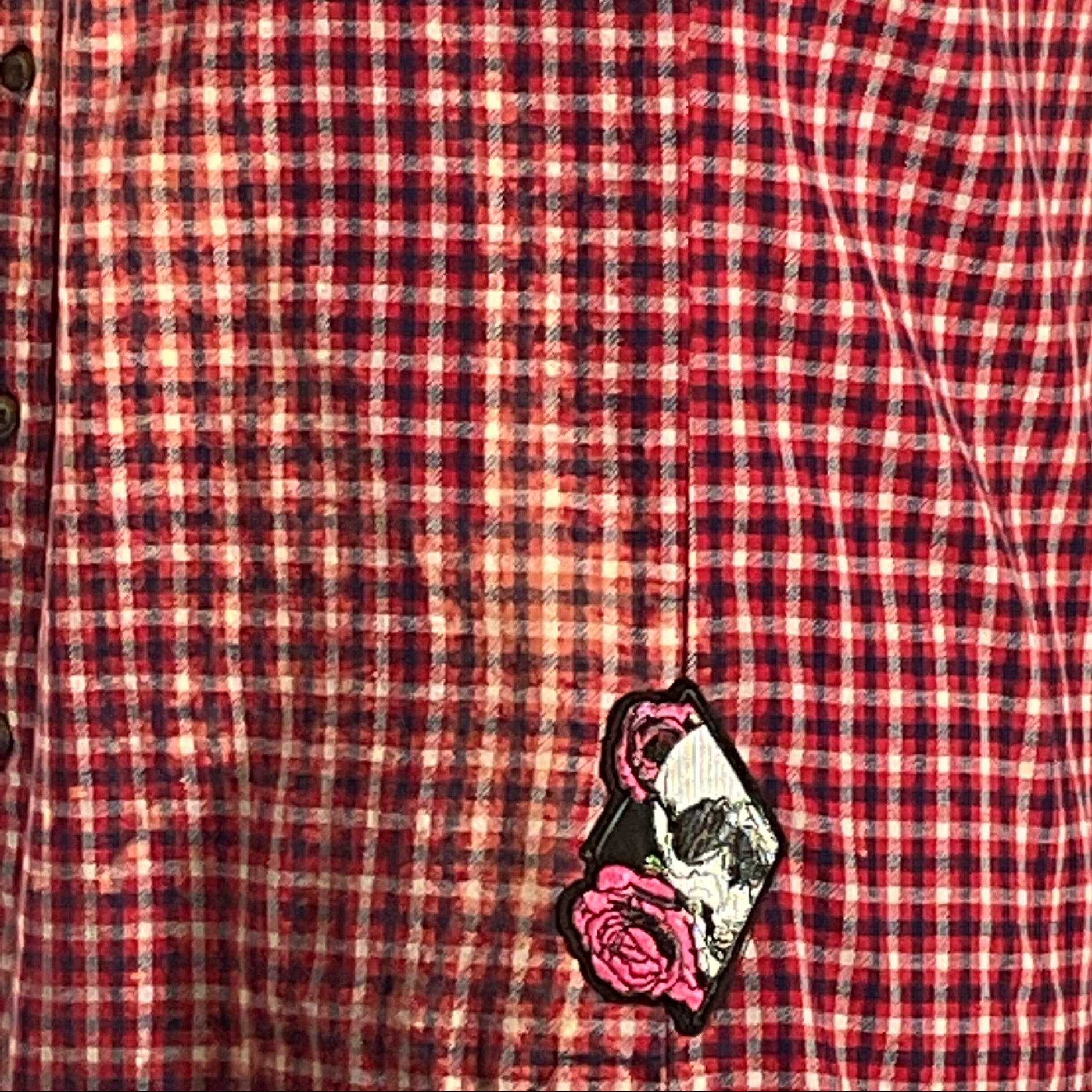 Red and black plaid flannel shirt with bleached treatment and hand-patched details, showcasing a vintage aesthetic and sustainable fashion.