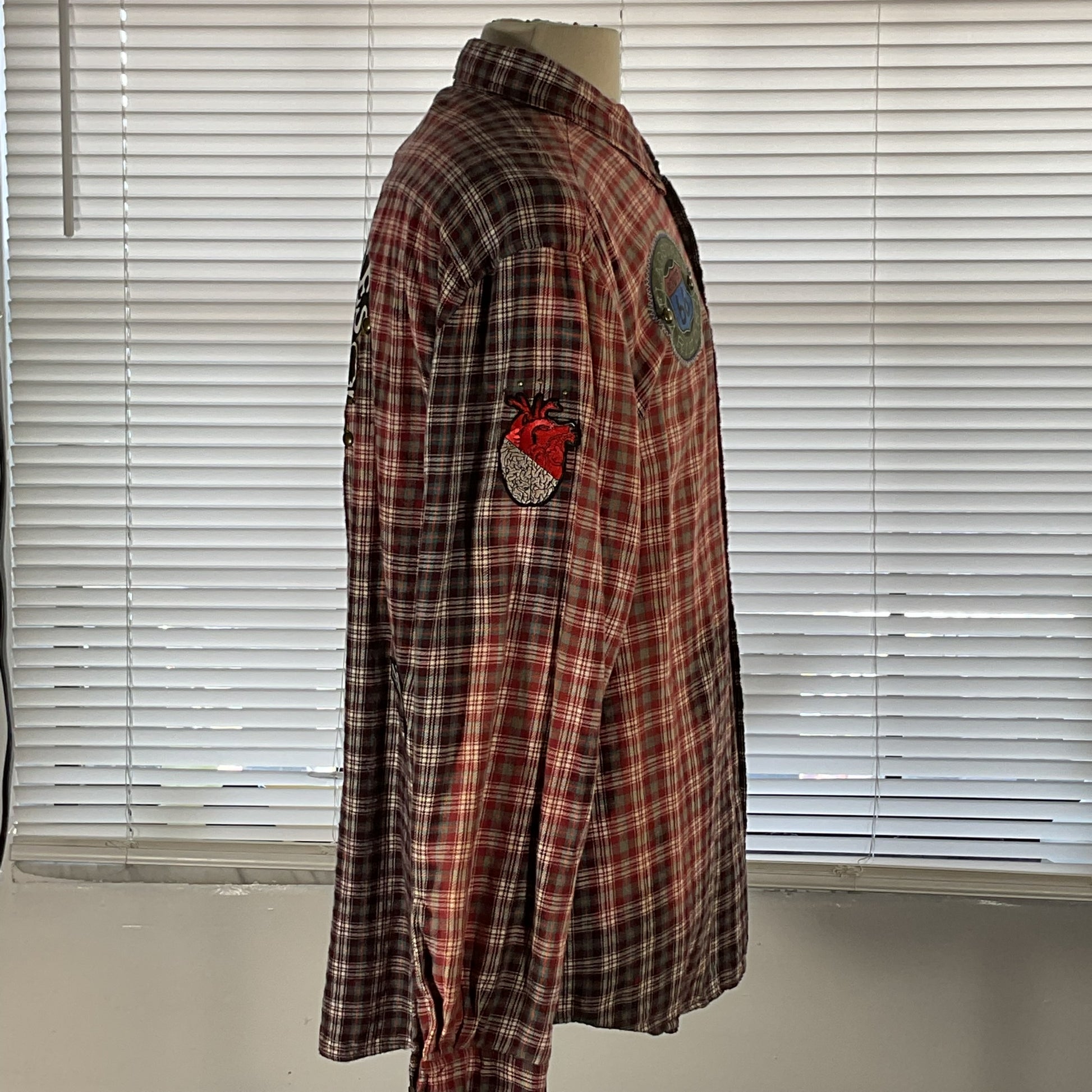 Mannequin displays NOBODY CARES | Men's Custom Long-Sleeve Flannel Shirt | LARGE, featuring plaid design and unique detailing, embodying DEVIOUS SAINT's bold, distinctive style.