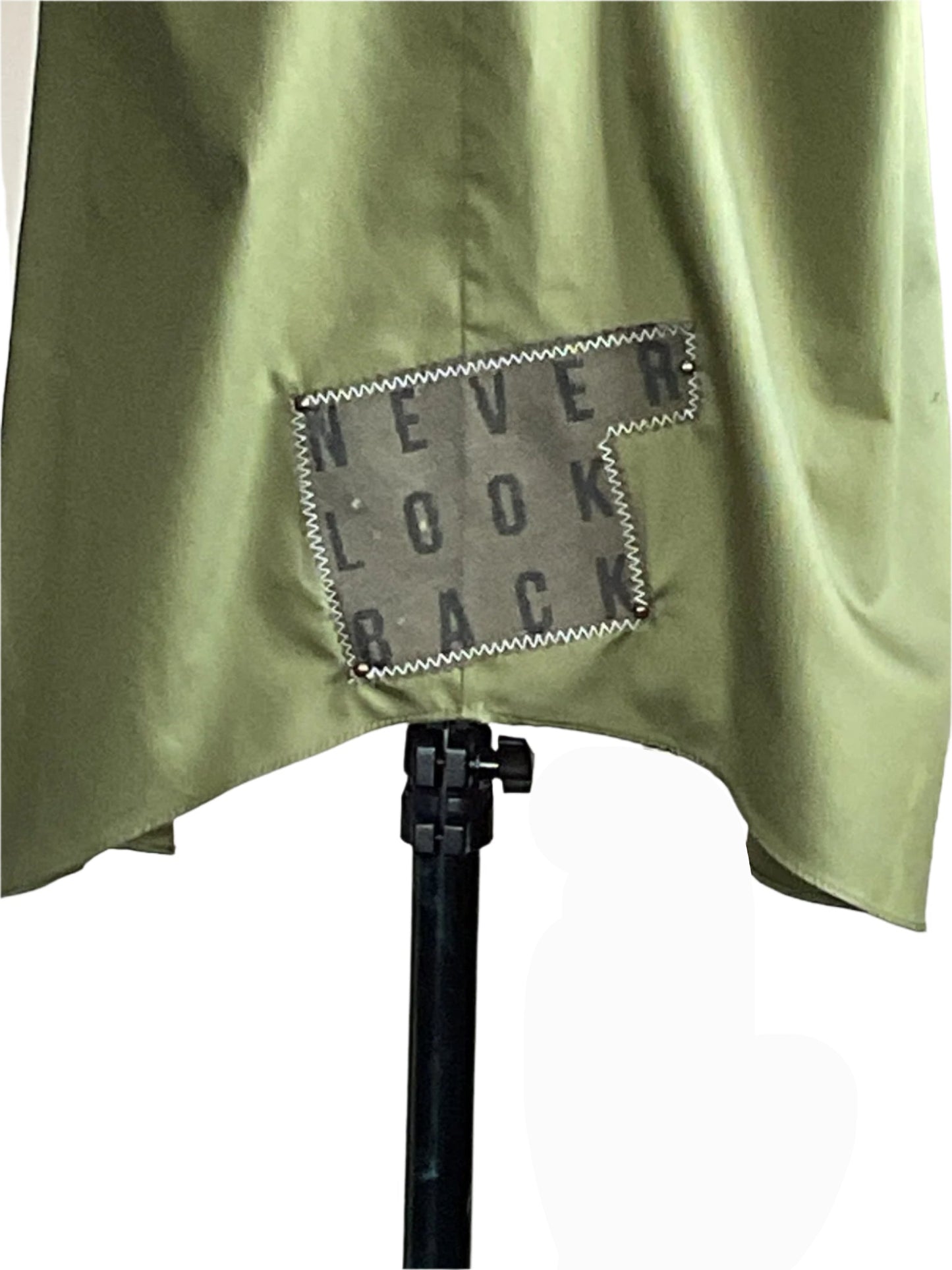 AS REAL AS IT GETS men's 3XL sleeveless shirt, olive-green with a gray NEVER LOOK BACK patch, draped over a stand, showcasing its bold, unique style.
