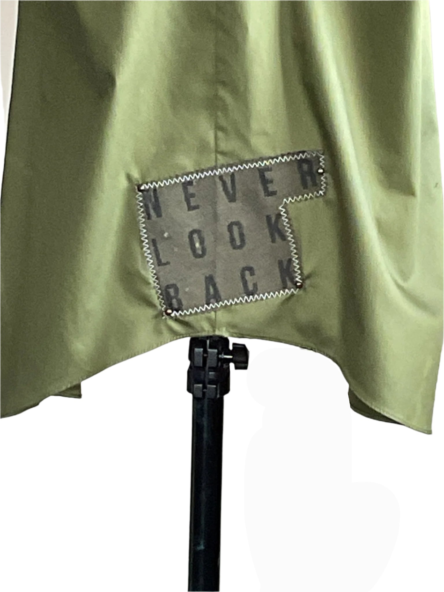 AS REAL AS IT GETS men's 3XL sleeveless shirt, olive-green with a gray NEVER LOOK BACK patch, draped over a stand, showcasing its bold, unique style.