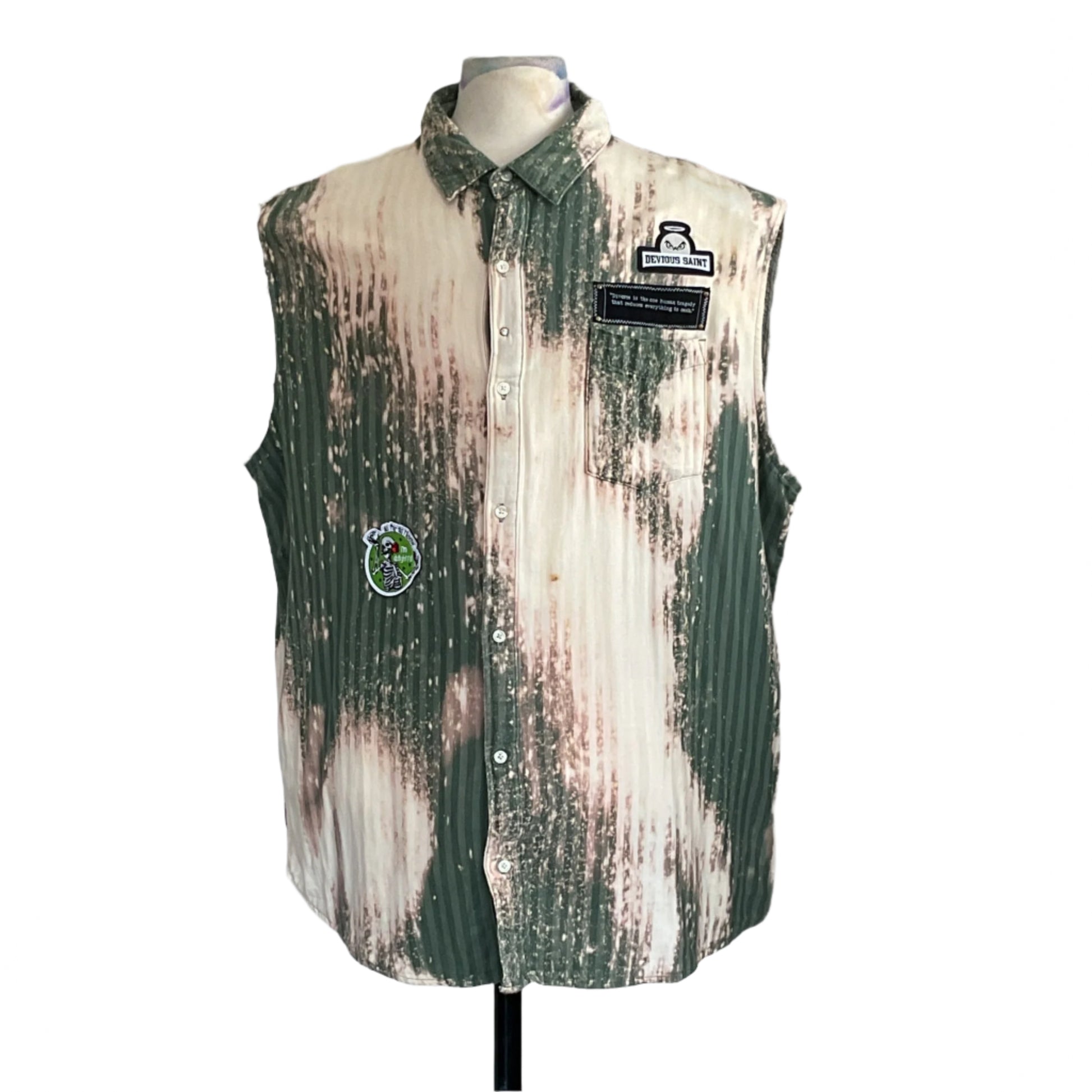 PATCHWORK BEAR sleeveless shirt on mannequin, green-and-white pin-striped with bleached patches, DEVIOUS SAINT patch, cartoon skeleton patch, evokes rugged, warrior spirit.