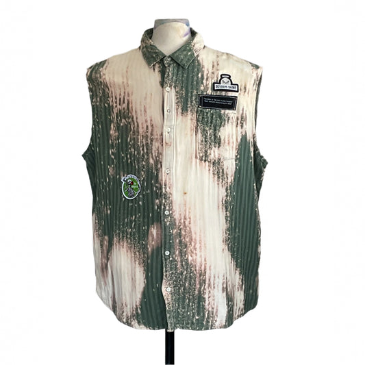 PATCHWORK BEAR sleeveless shirt on mannequin, green-and-white pin-striped with bleached patches, DEVIOUS SAINT patch, cartoon skeleton patch, evokes rugged, warrior spirit.