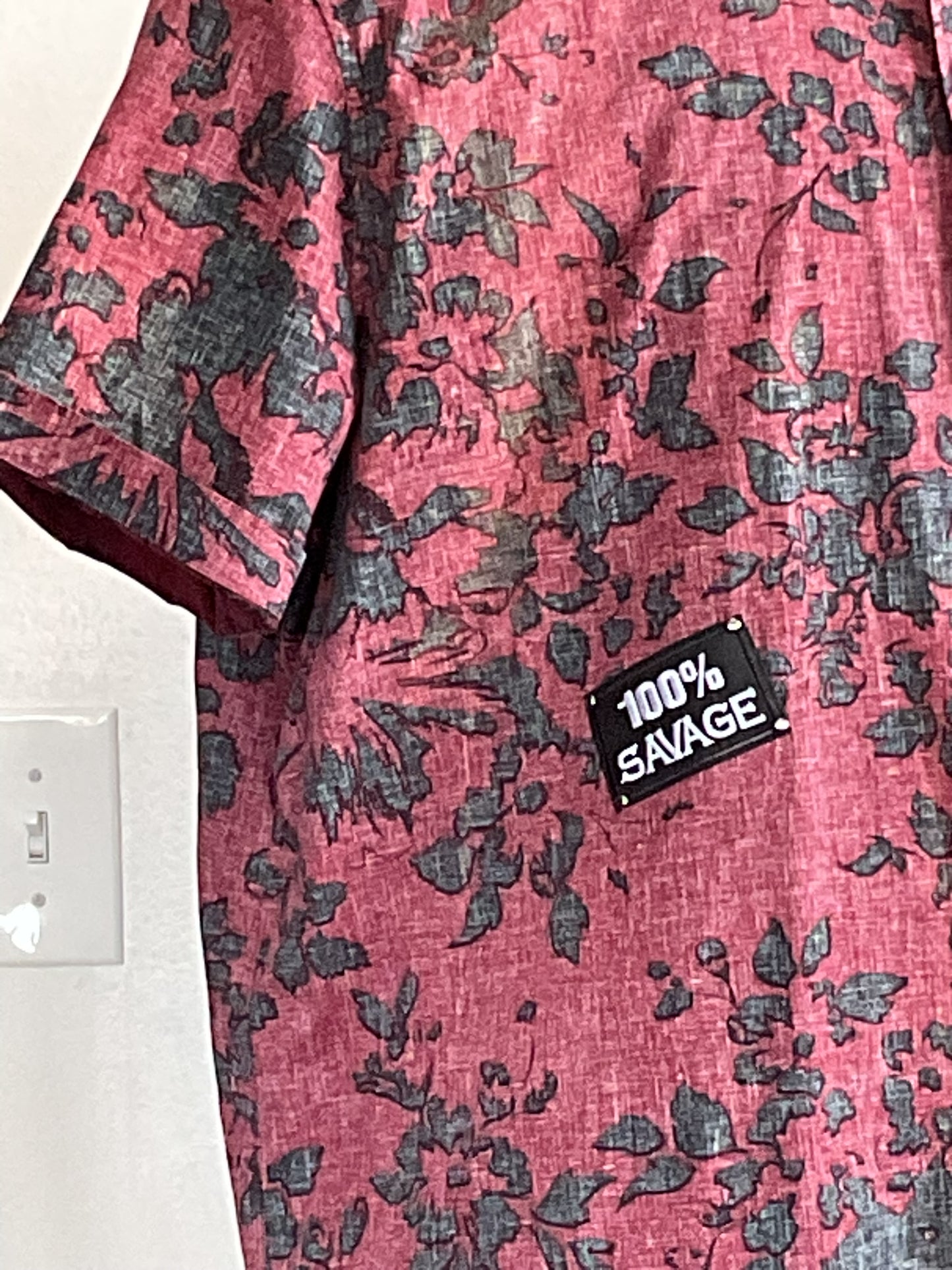 Red short-sleeved shirt with black floral print and 100% SAVAGE patch on front, embodying playful style. Size 2XL, from DEVIOUS SAINT's unique collection.