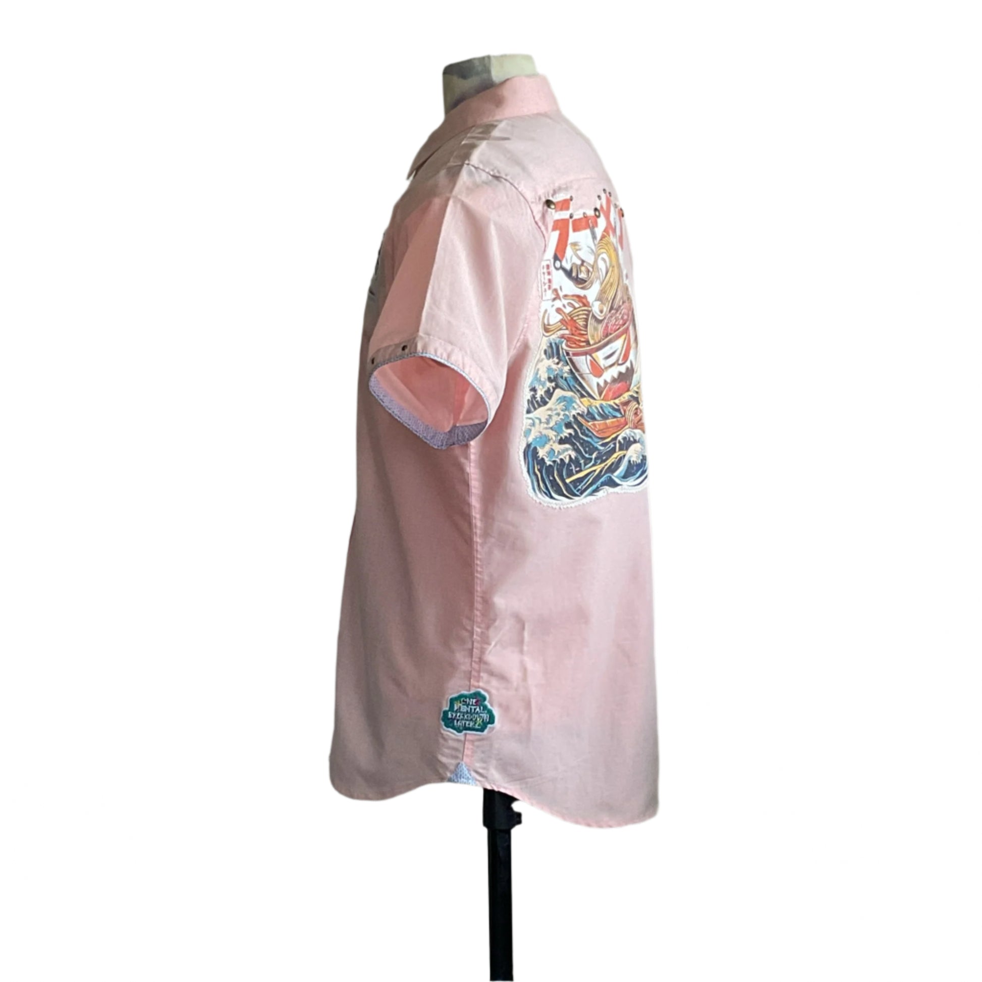 Light-pink short-sleeve shirt, RAMEN, features a vibrant ramen bowl graphic with ocean waves on the back, highlighting bold, wearable art in extra-large size.