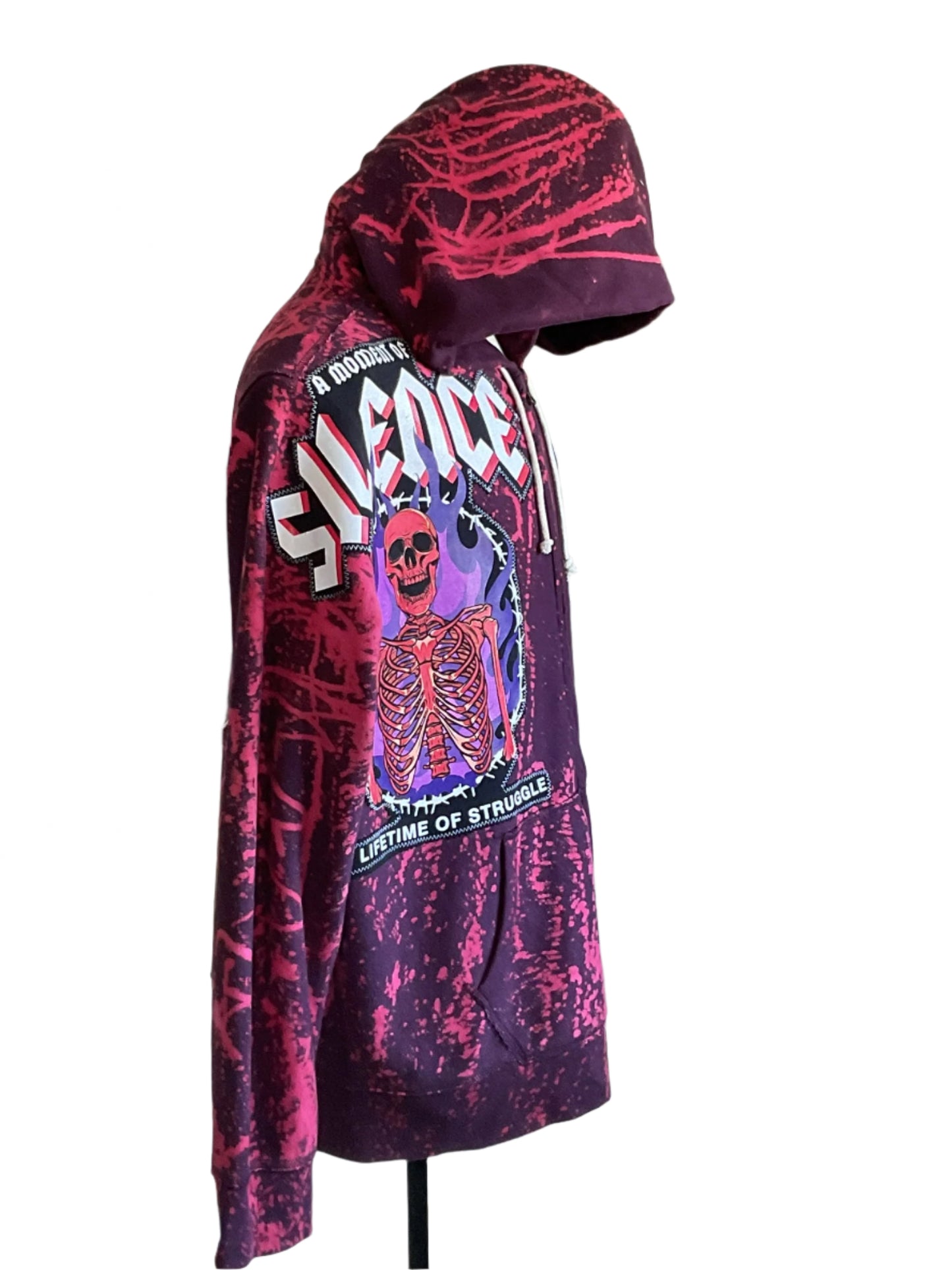 Dark purple splatter-dyed hoodie with flaming skeleton graphic and text A Moment of Silence, Lifetime of Struggle; features kangaroo pocket and white draw-cords.