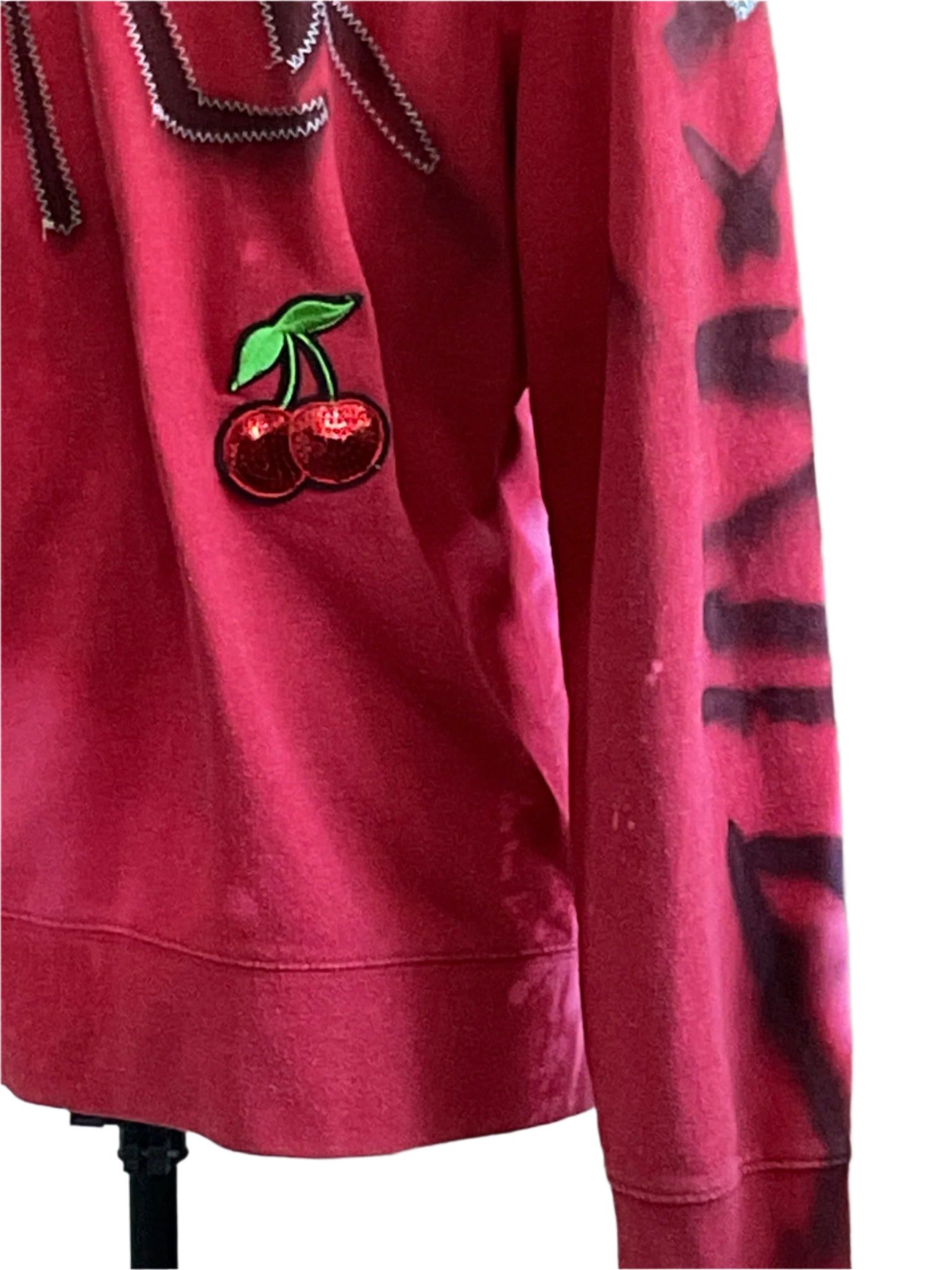 DEVIOUS SAINT Custom Men's Hoodie with zig-zag trim, sequined cherry patch, graffiti-style sleeve print, and kangaroo pocket, offering bold style and comfort.